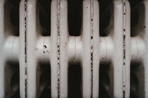 Close-up of a white cast iron radiator with visible rust and wear.
