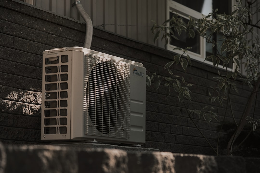 Outdoor air conditioning unit mounted on a dark brick wall.